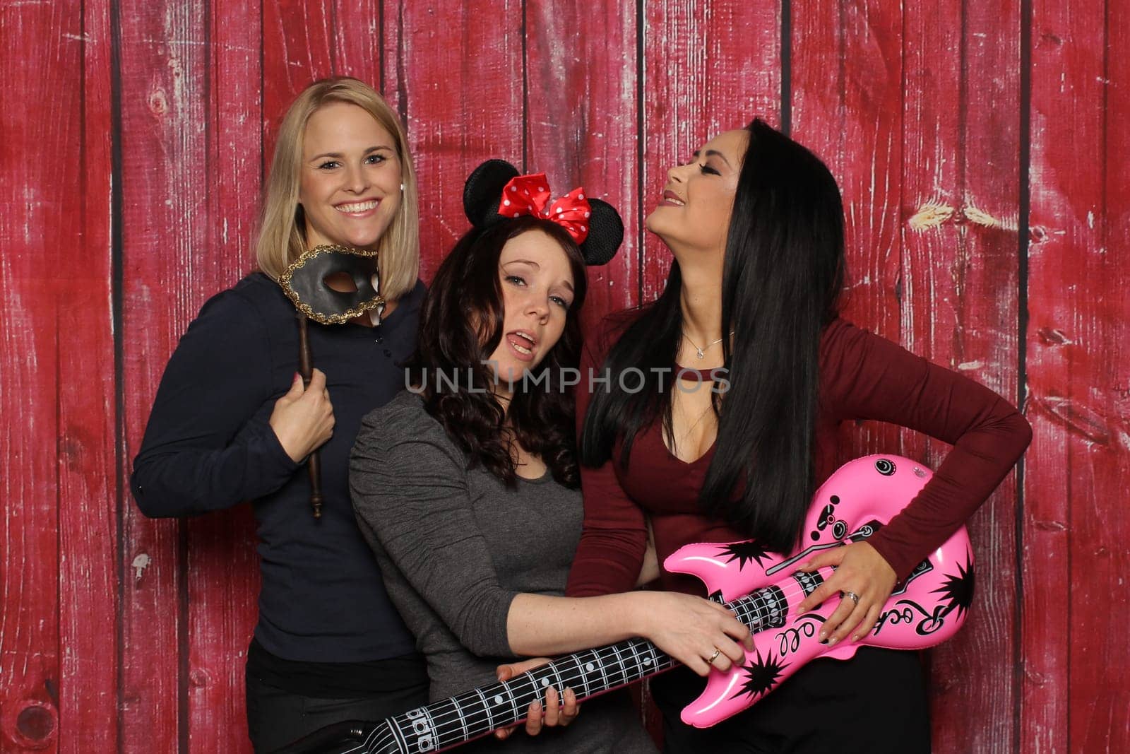 Girl trio fools around in front of a photo booth