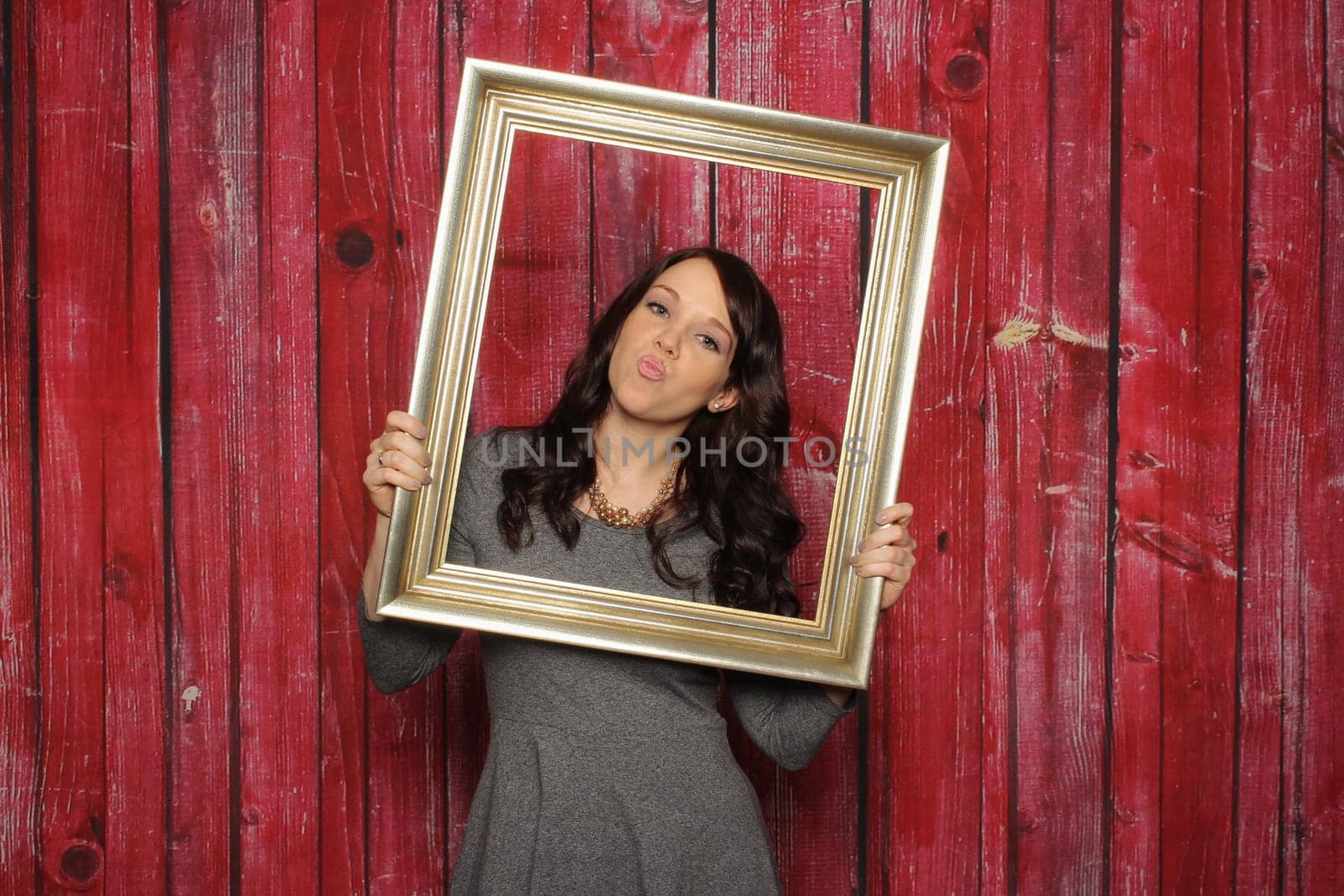 Young woman looks through a picture frame and gives an air kiss