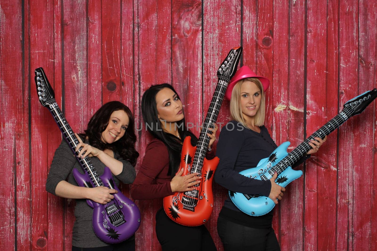 Three young women play on plastic guitars