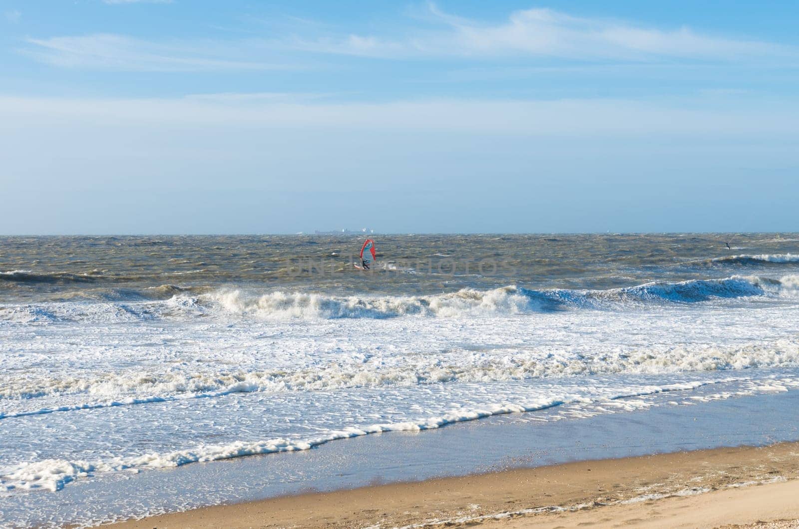single wind surfer braving the waves on a rough north sea