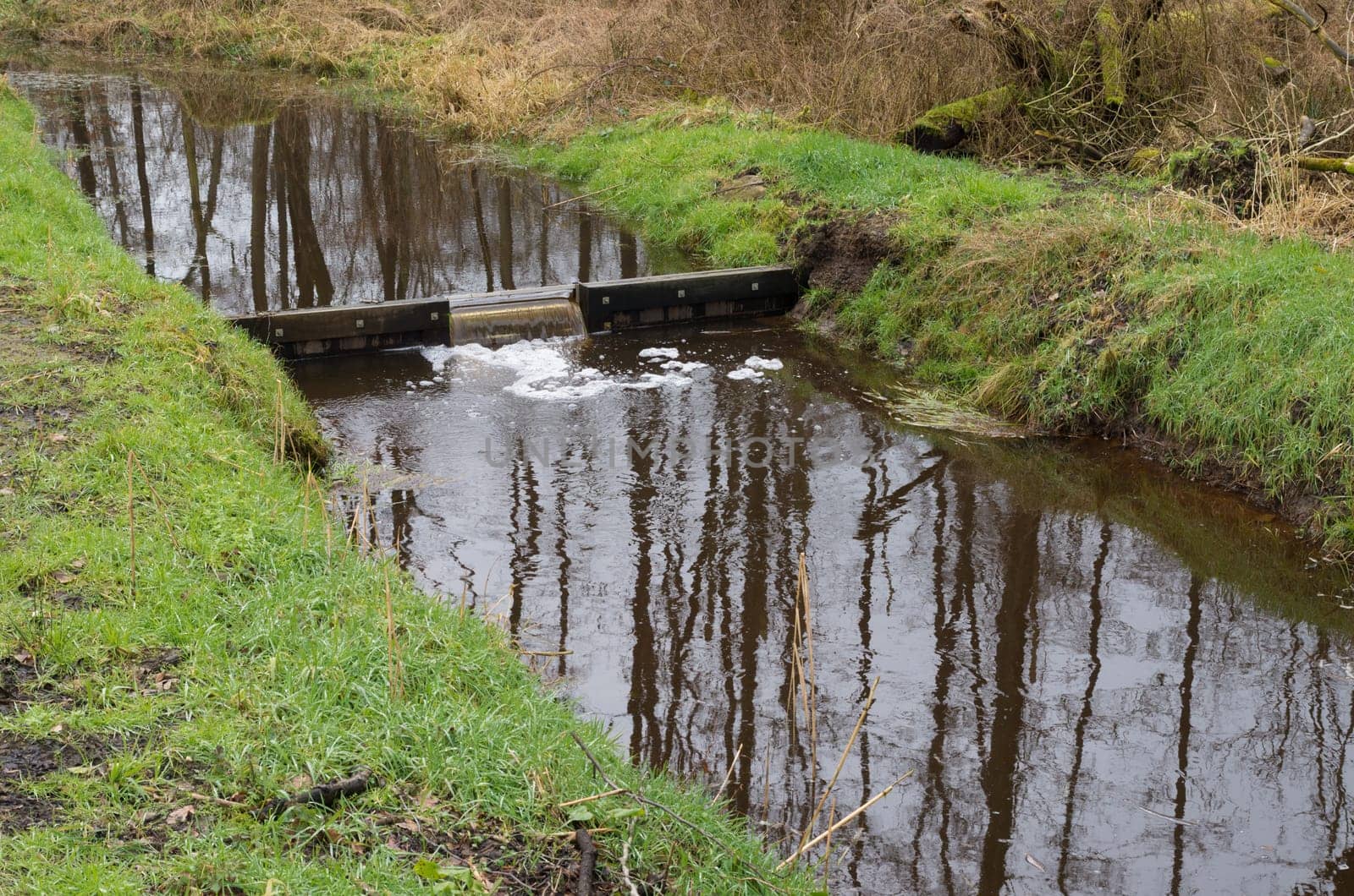 small ditch with a weir in winter time