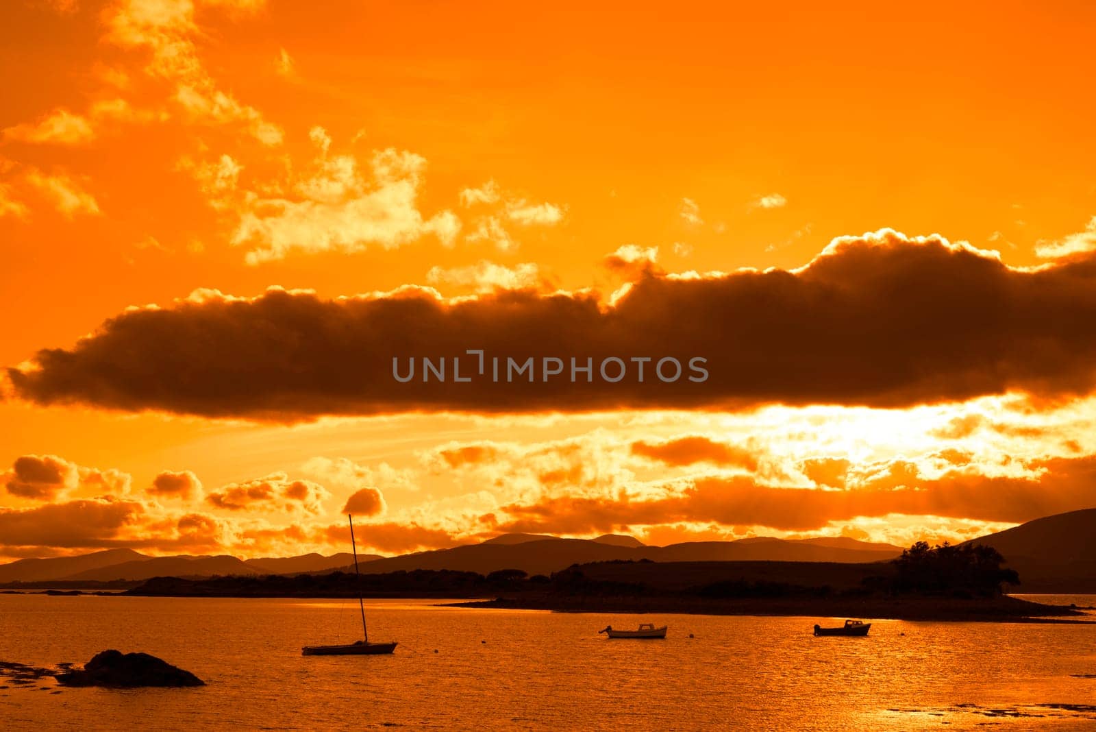 boats in a quiet bay with island near kenmare on the wild atlantic way ireland with an orange sunset