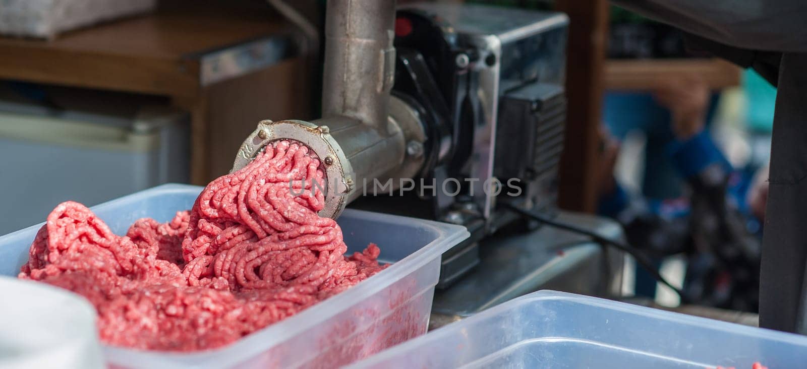 Tray of fresh minced meat. machine that puts the meat back into the machine.