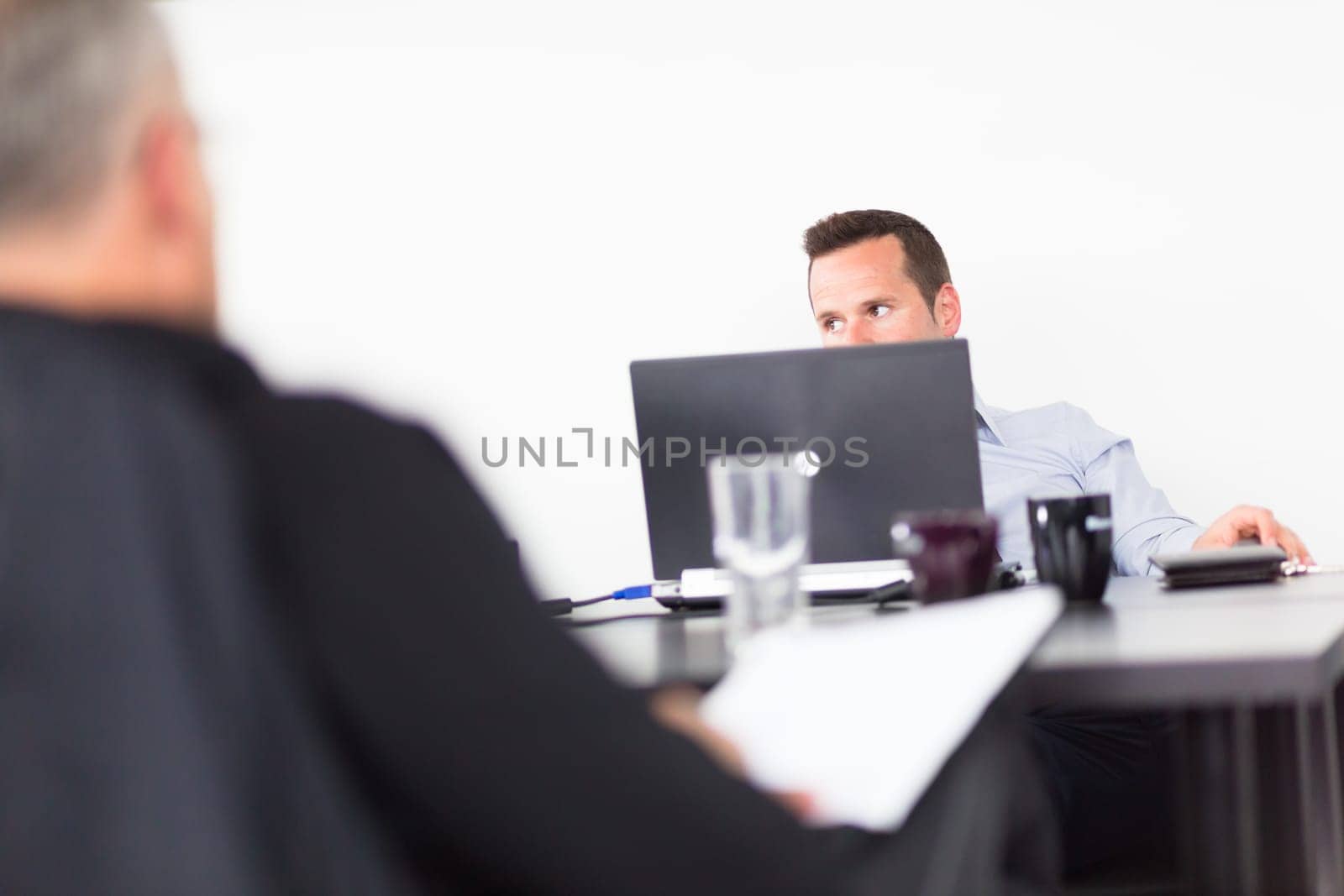 Workplace in modern office with businessman working on laptop during the meeting.