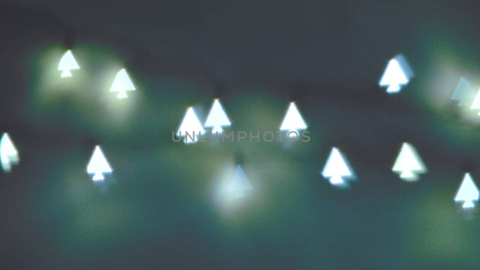 Bokeh Christmas lights in shapes of little Christmas trees. Happy Christmas time background.