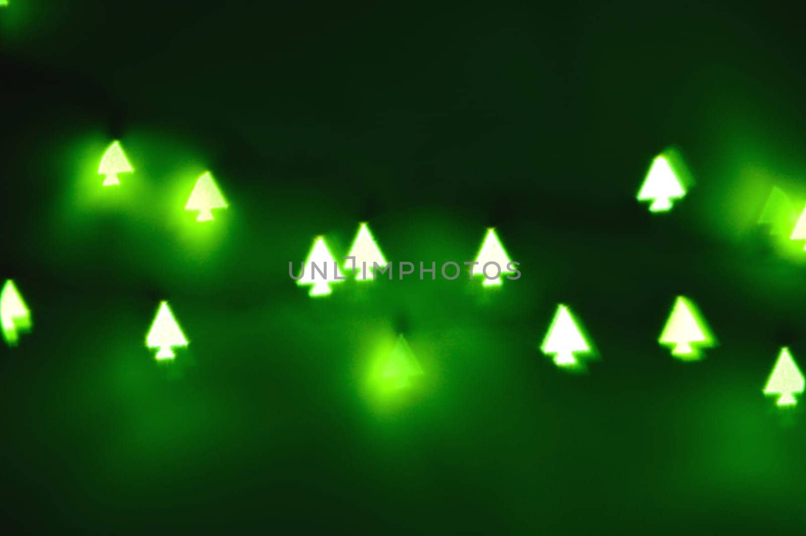 Bokeh Christmas lights in shapes of little Christmas trees. Happy Christmas time background.