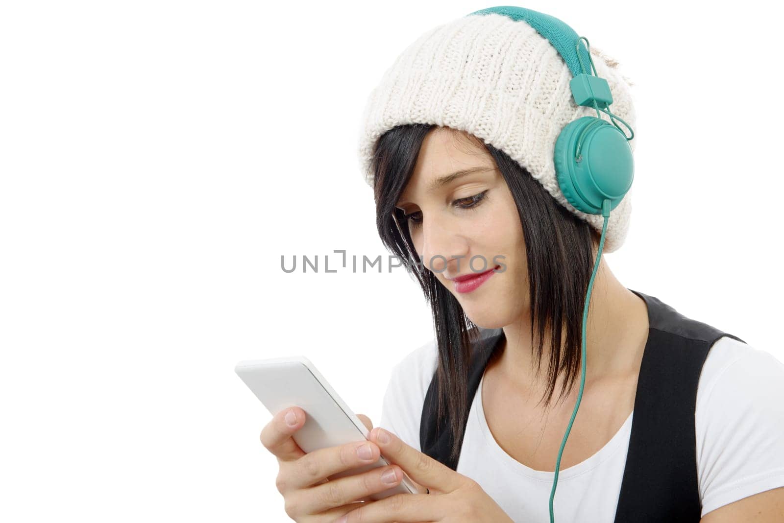young brunette listening to music with headphones and  phone on white