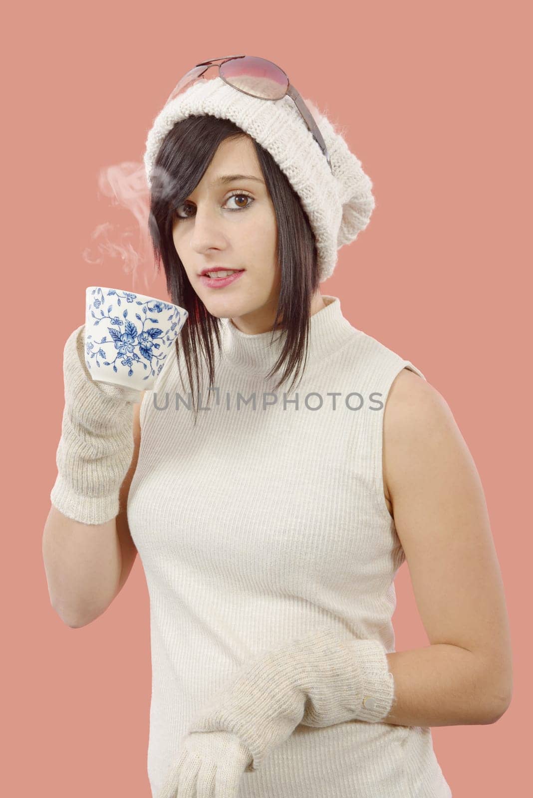 pretty young brunette woman with a cup of tea on pink background