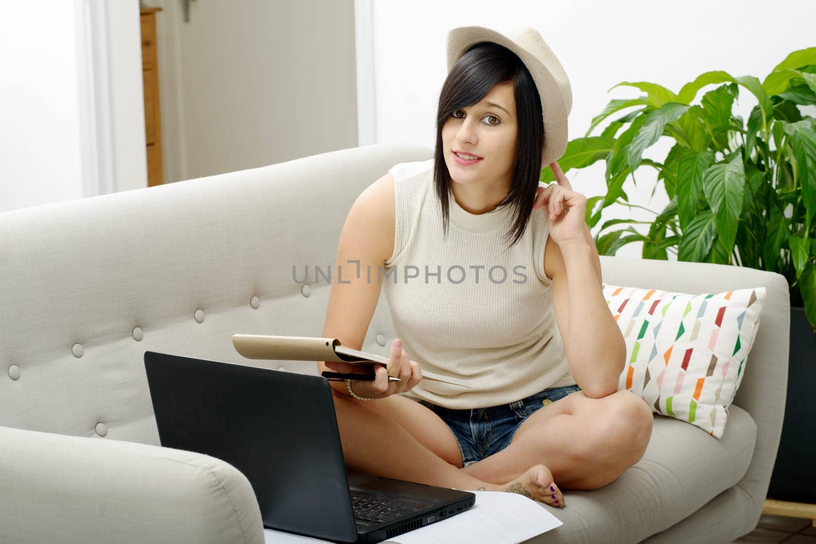 young brunette girl student sitting on the couch with a laptop