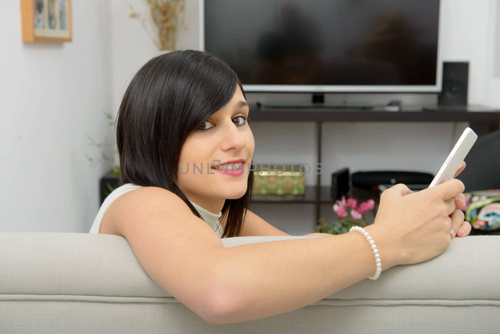 young brunette girl student sitting on the couch with phone
