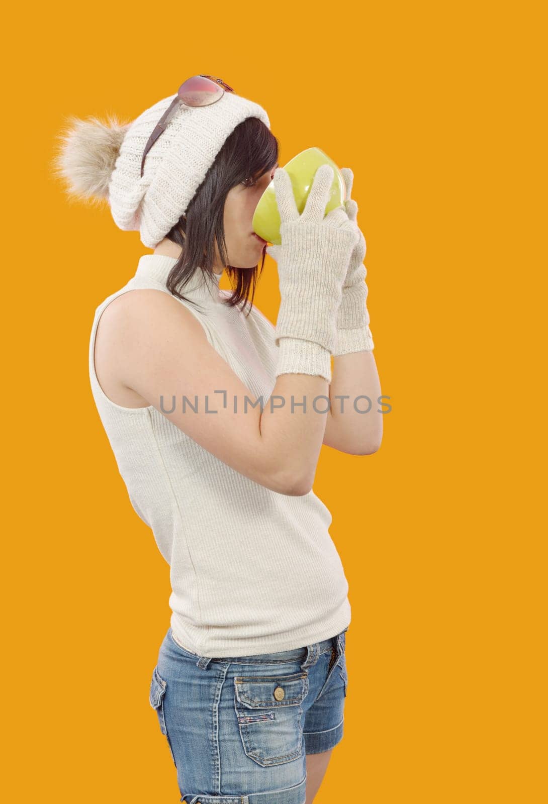pretty young brunette woman with a cup of tea on yellow background