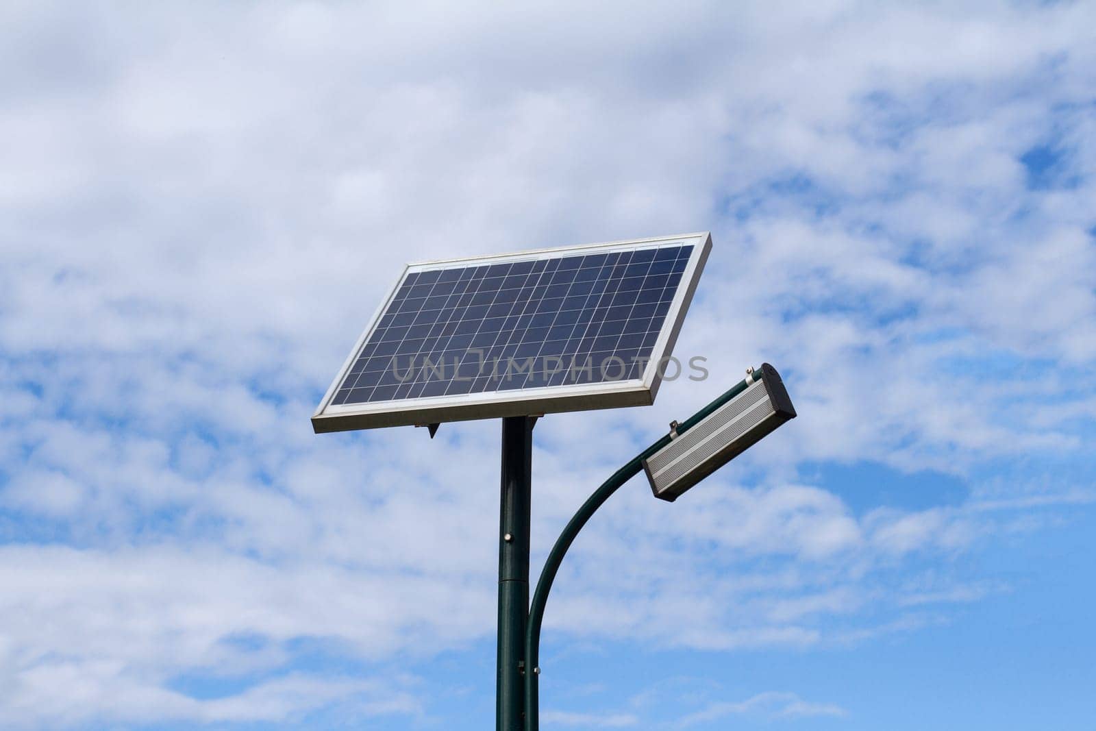 Public city light with solar panel powered on blue sky with clouds