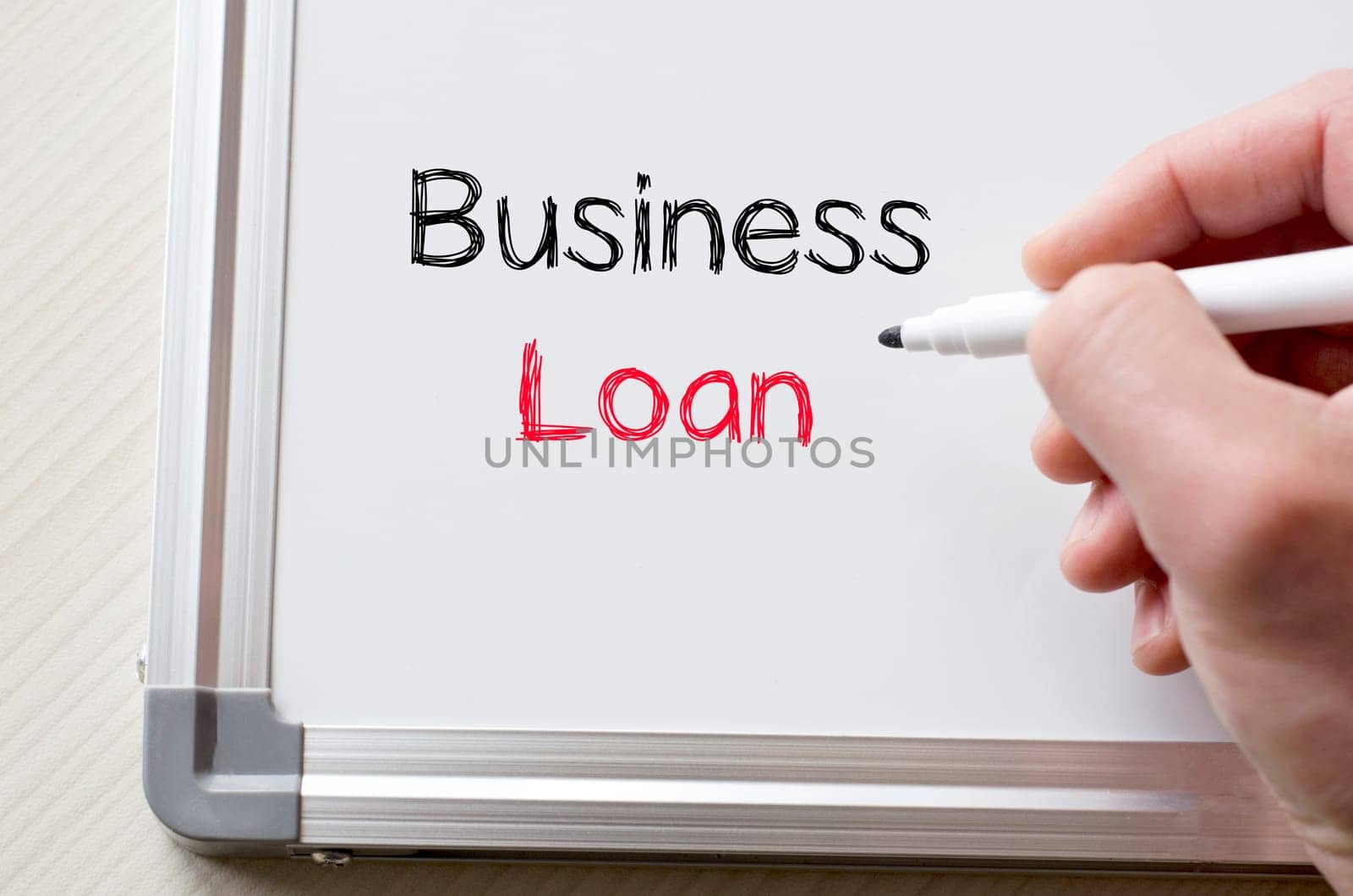 Human hand writing business loan on whiteboard