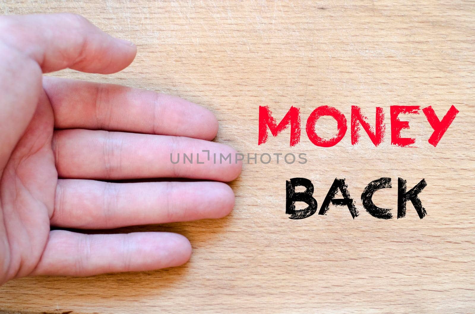 Human hand over wooden background and money back text concept