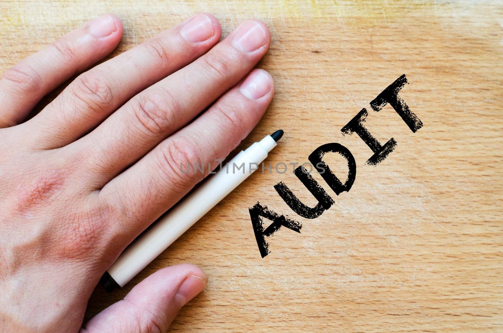 Human hand over wooden background and audit text concept