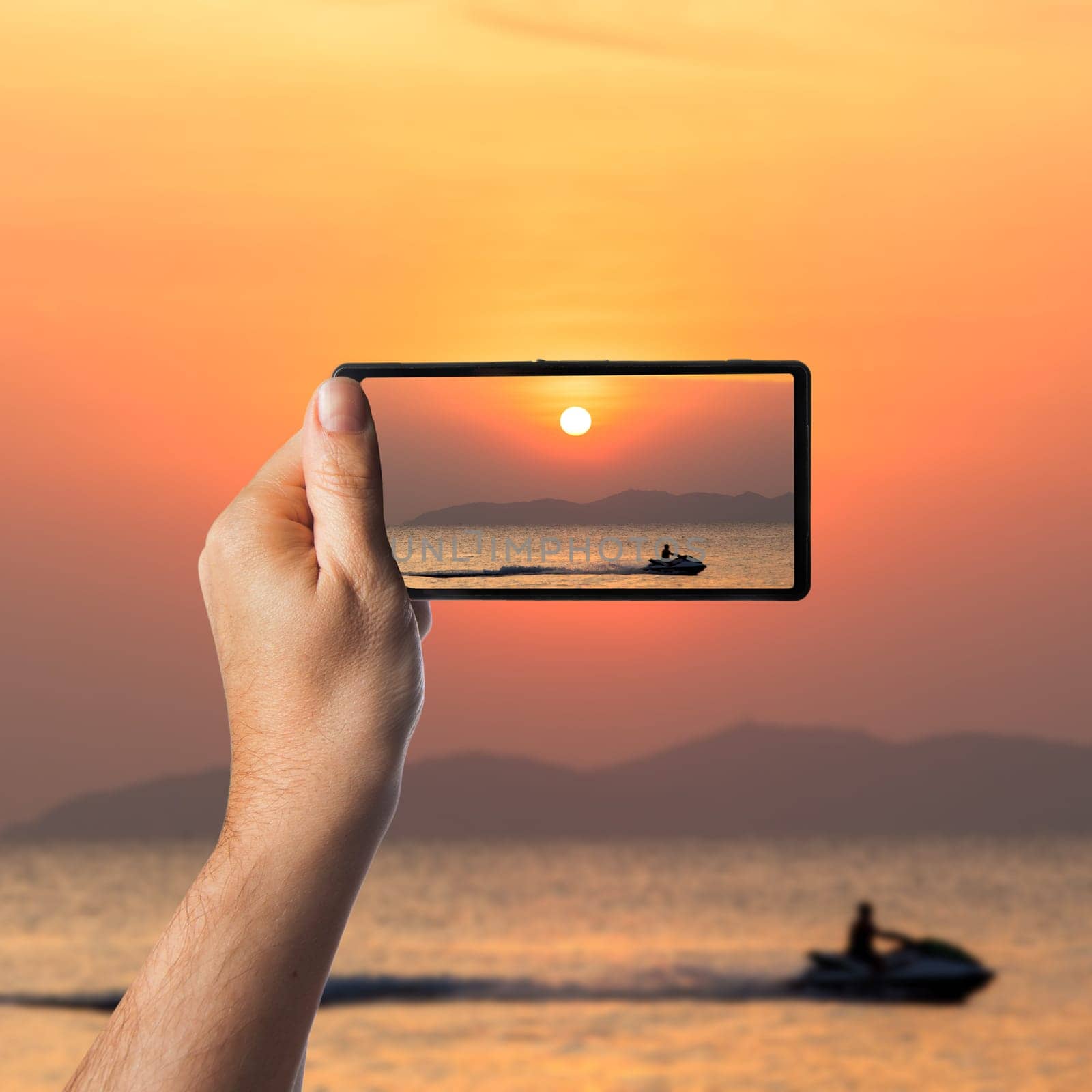 Nice sunset. Hand with a smartphone. Taking photo