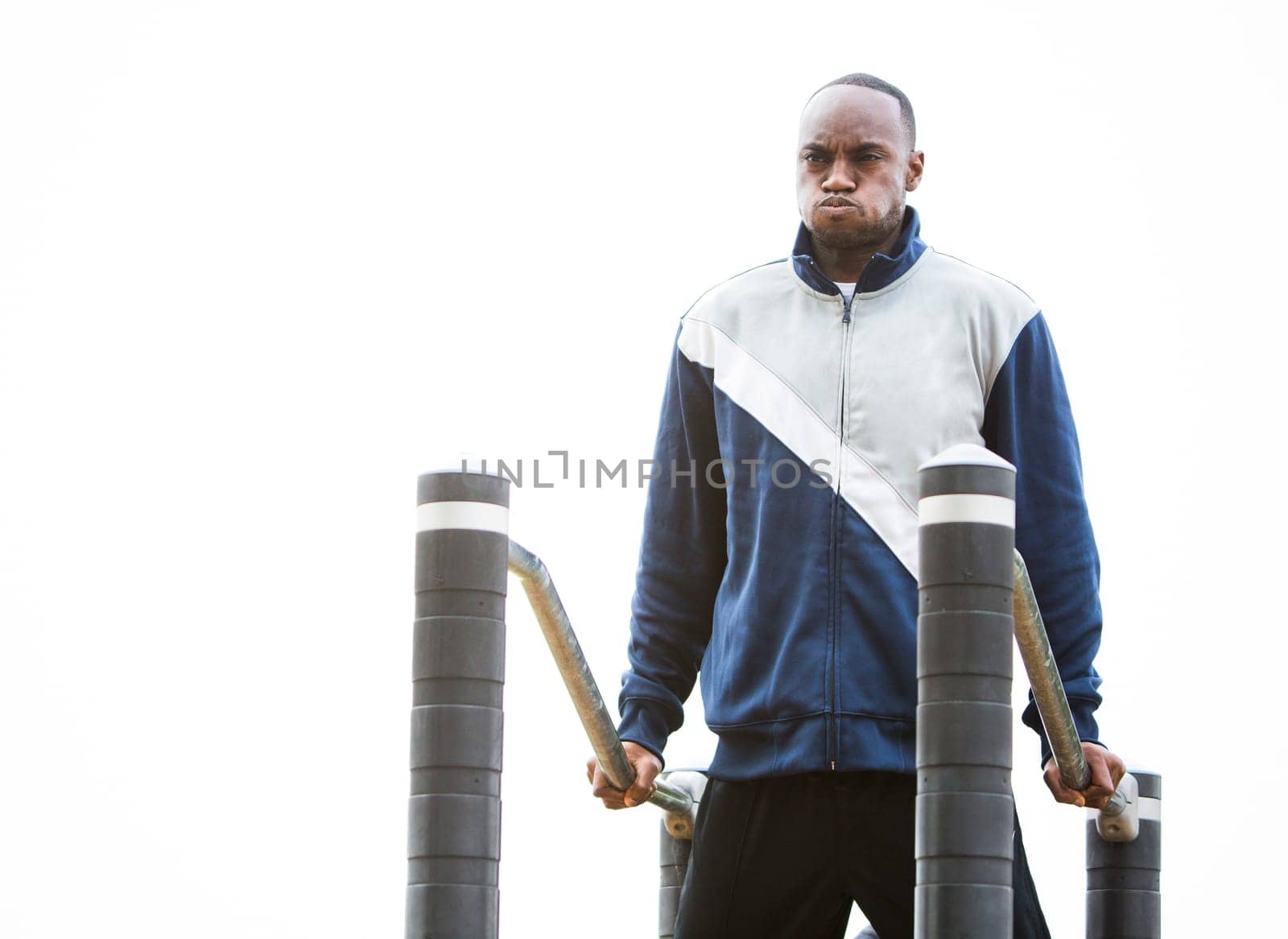 Active black man in training suit exercising at outdoor gym