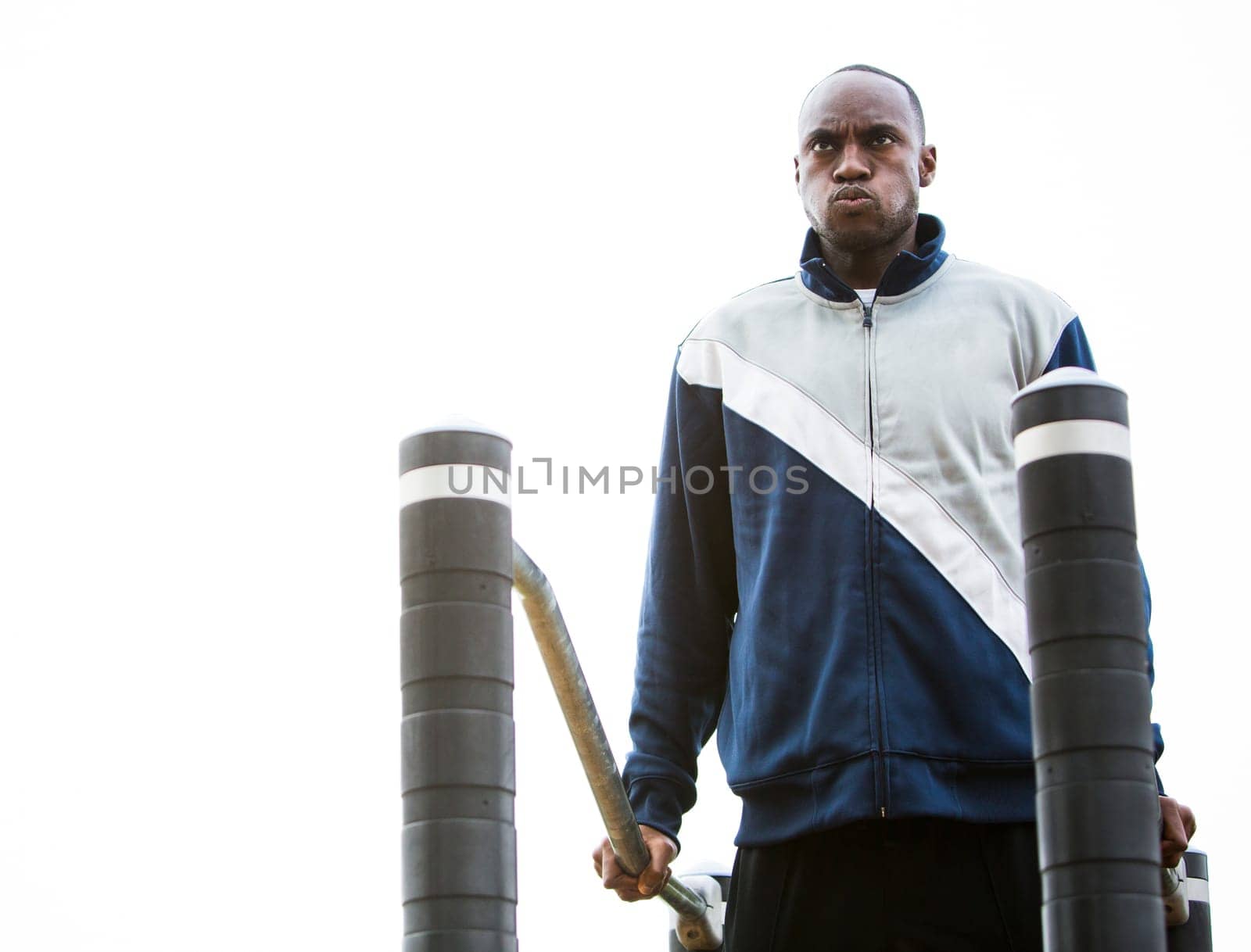 Active black man in training suit exercising at outdoor gym