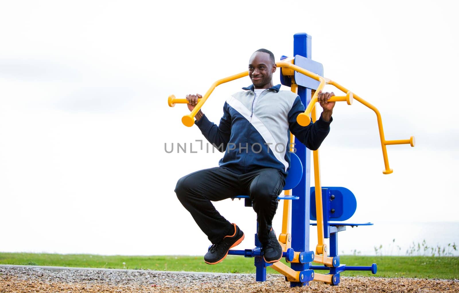 Active black man in training suit exercising at outdoor gym