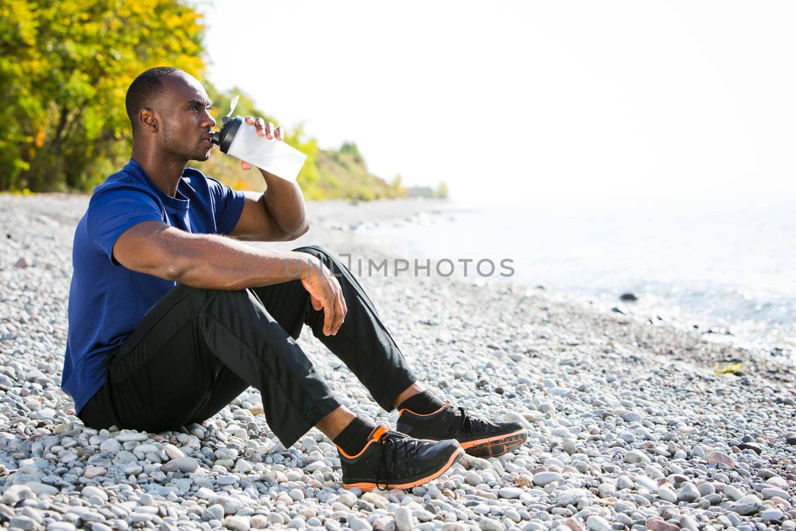 young black man wearing athletic wear sitting on the beach