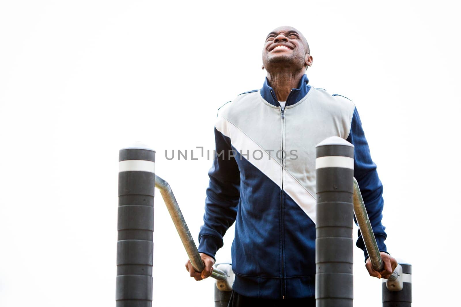 Active black man in training suit exercising at outdoor gym