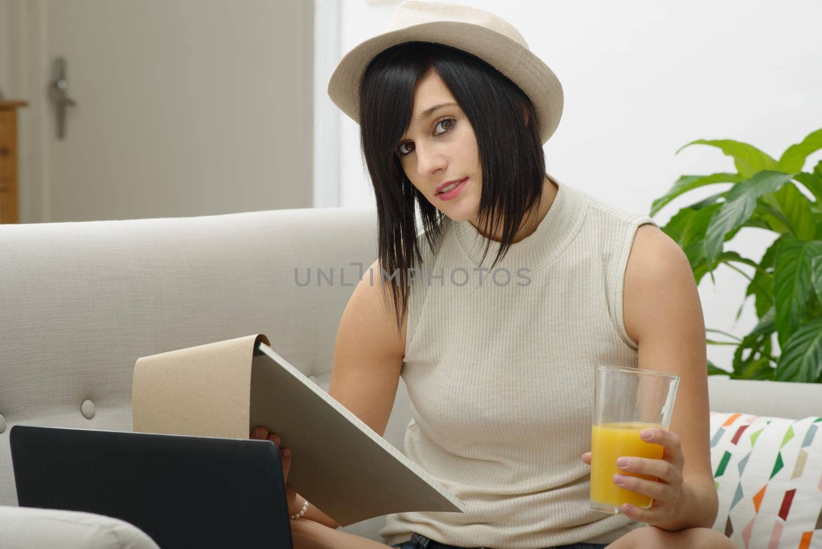 pretty young student drinking orange juice in couch at home