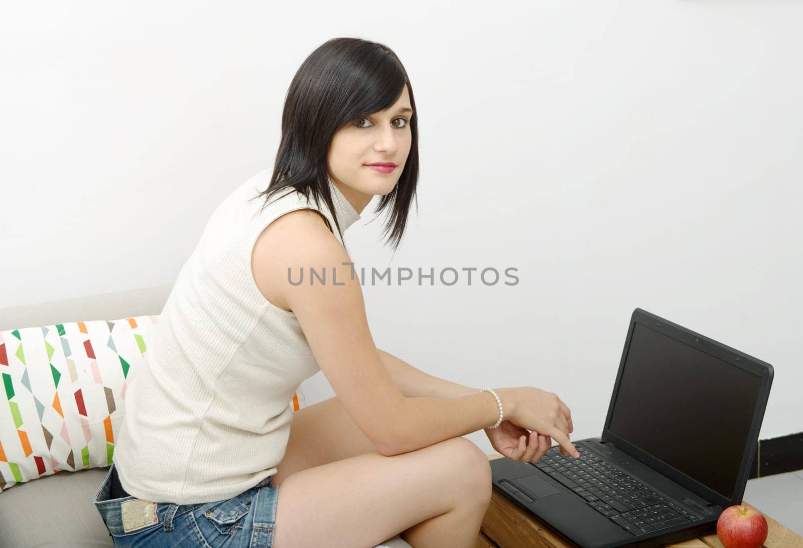 young brunette girl student sitting on the couch with a laptop
