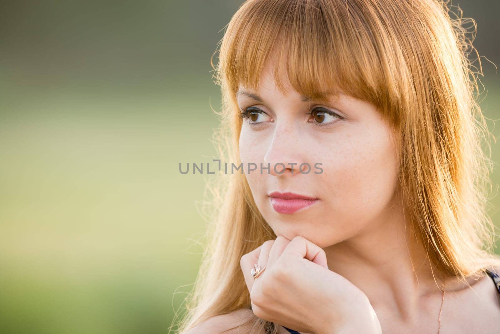 Up portrait of a girl gazing to the left, creating a soft green background