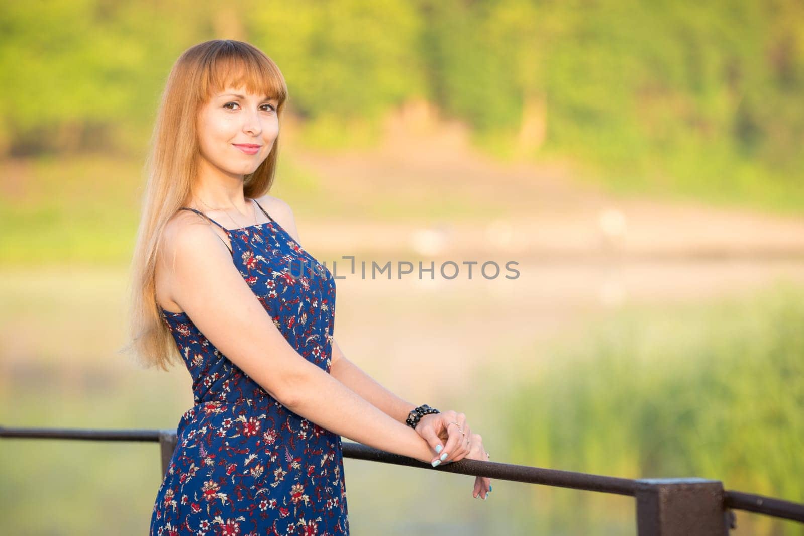 The charming young girl standing on a rustic bridge at dawn sun