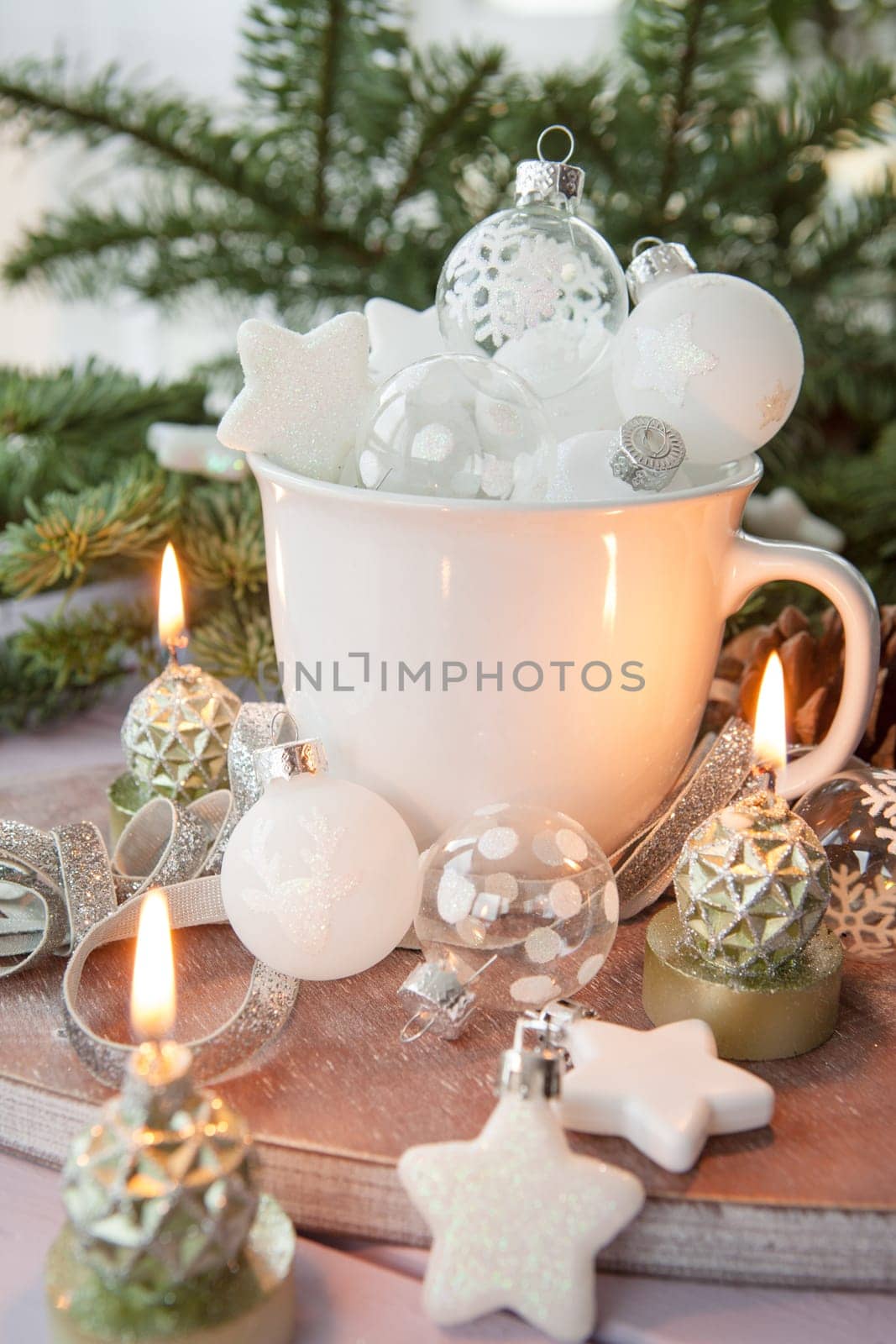 White cup with Christmas tree balls in front of fir branches