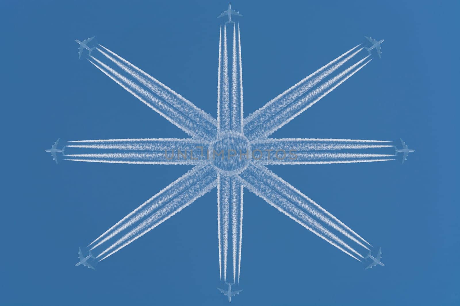 Eight aircraft at high altitude fly in star-shaped formation. Contrails against a dark blue sky..