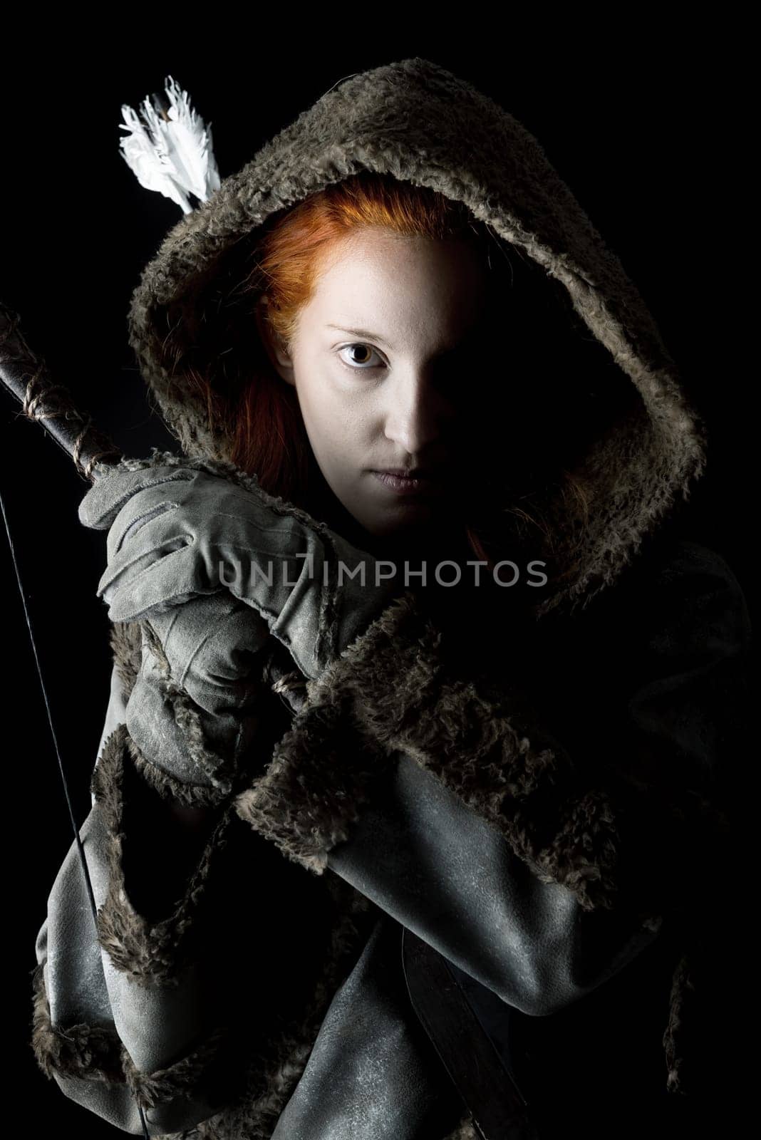 girl archer in a costume with bow isolated in a dark background