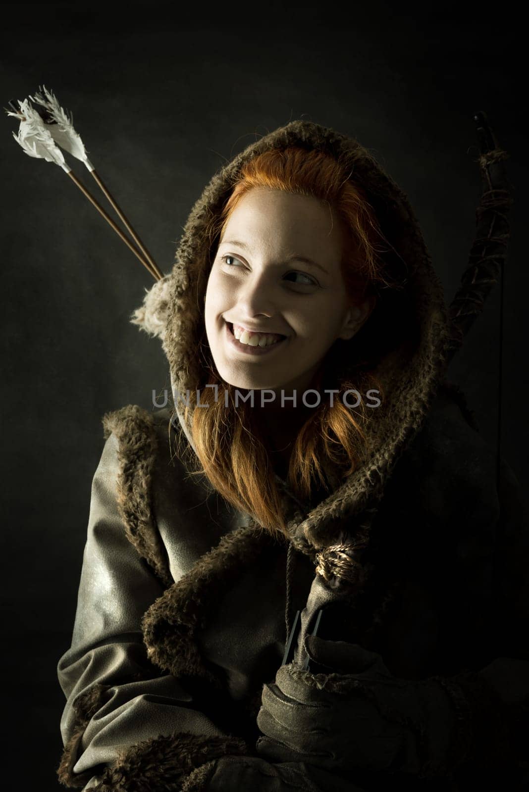 girl archer in a costume with bow isolated in a dark background