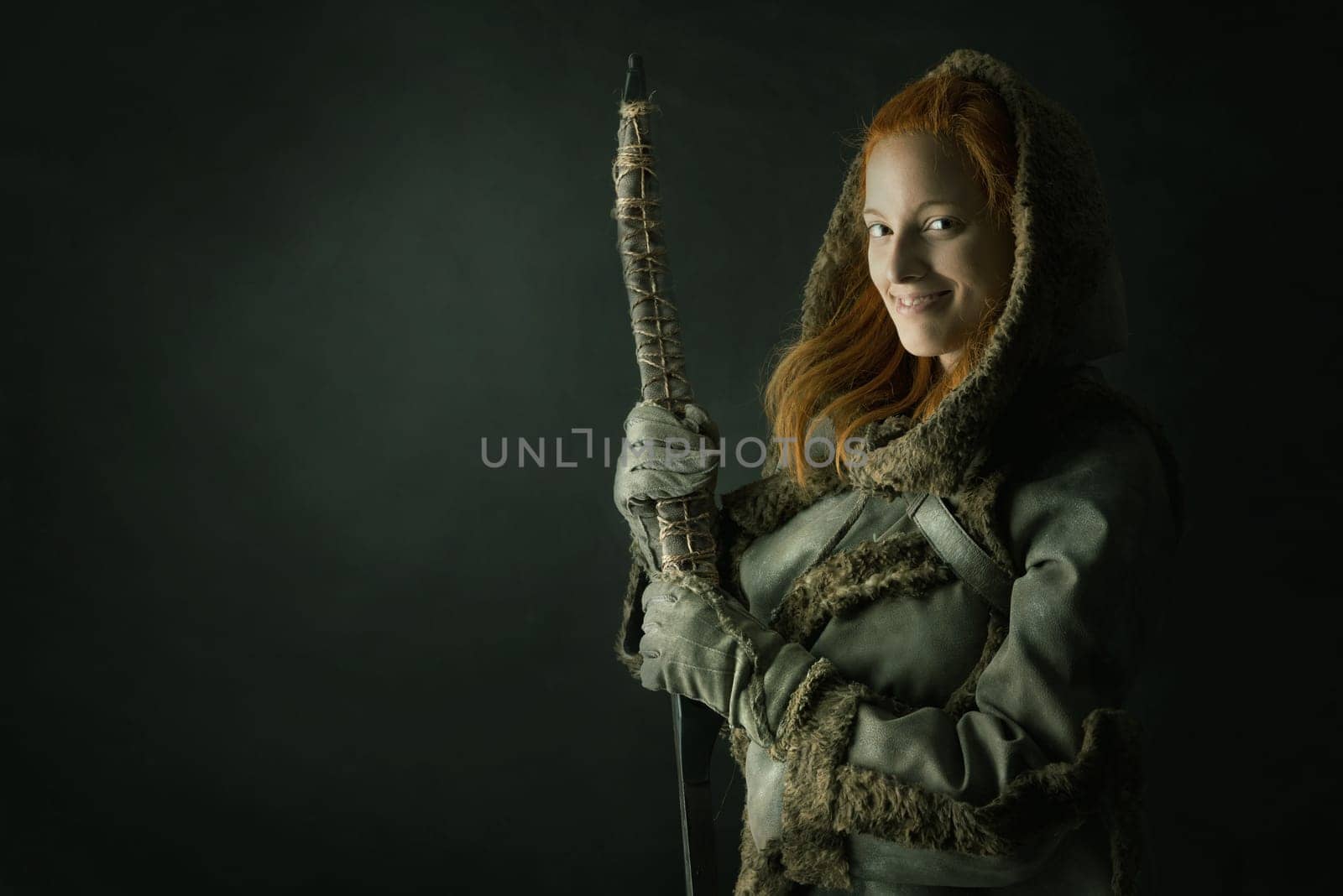 girl archer in a costume with bow isolated in a dark background