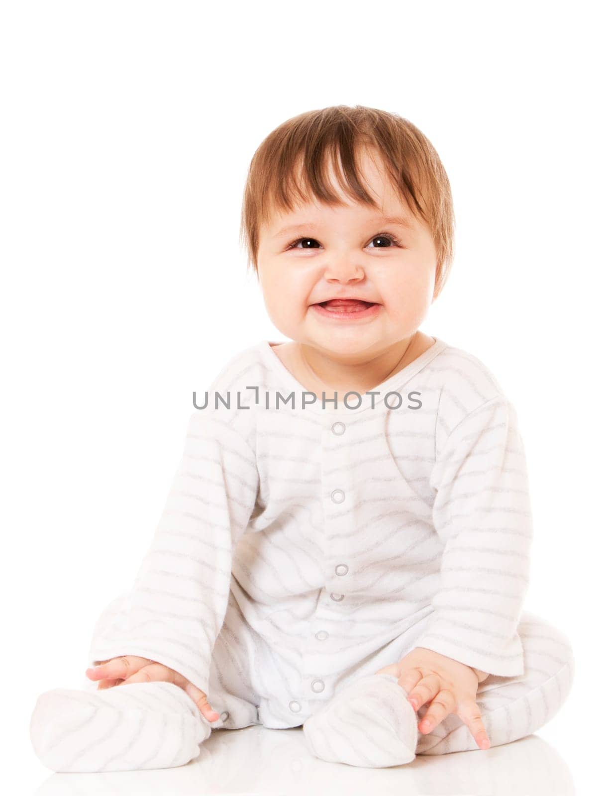 Cute baby sitting on the white floor background, wearing a sliders and smiling big. Isolated.