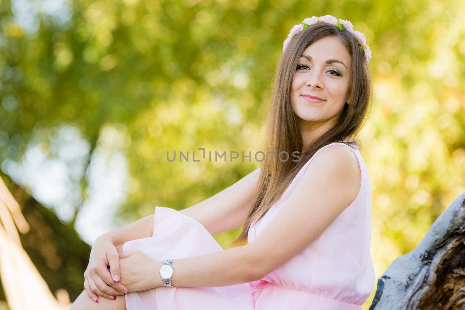 Beautiful girl sits on a background illuminated by the sun leaves