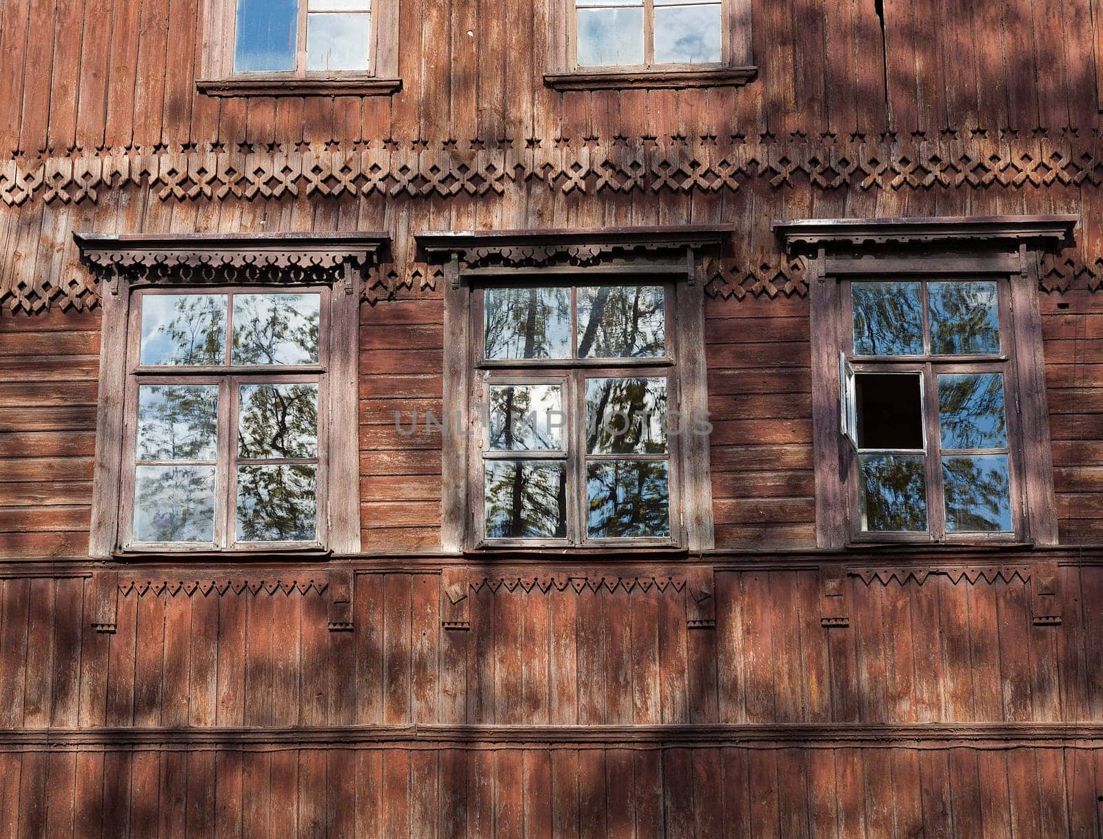 photographed close-up of the old red wooden houses with windows. In the house no one lives