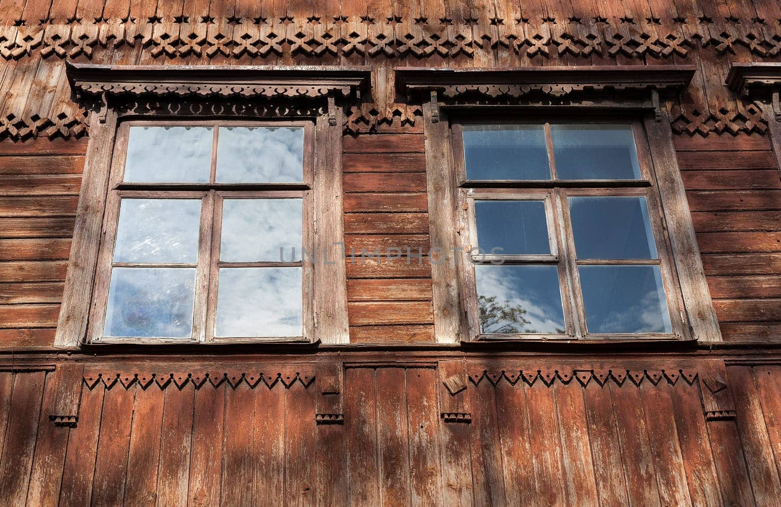 photographed close-up of the old red wooden houses with windows. In the house no one lives