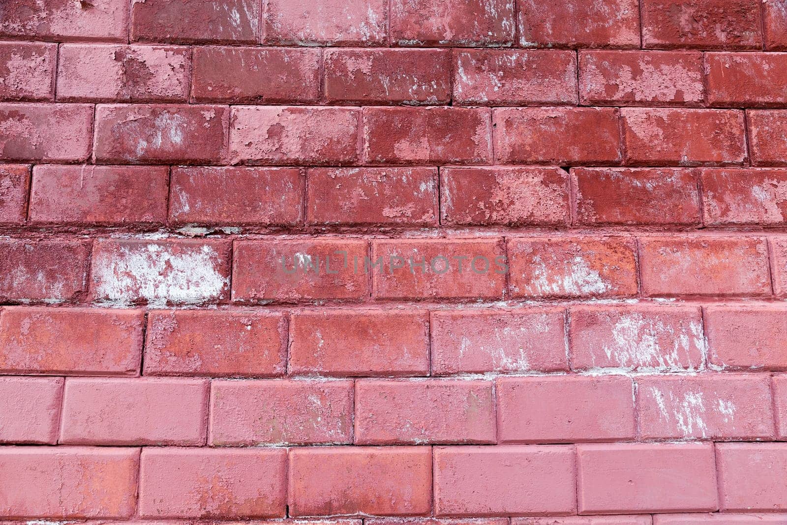 photographed close-up part of the wall of brick, painted in red color, which has been spoiled with time