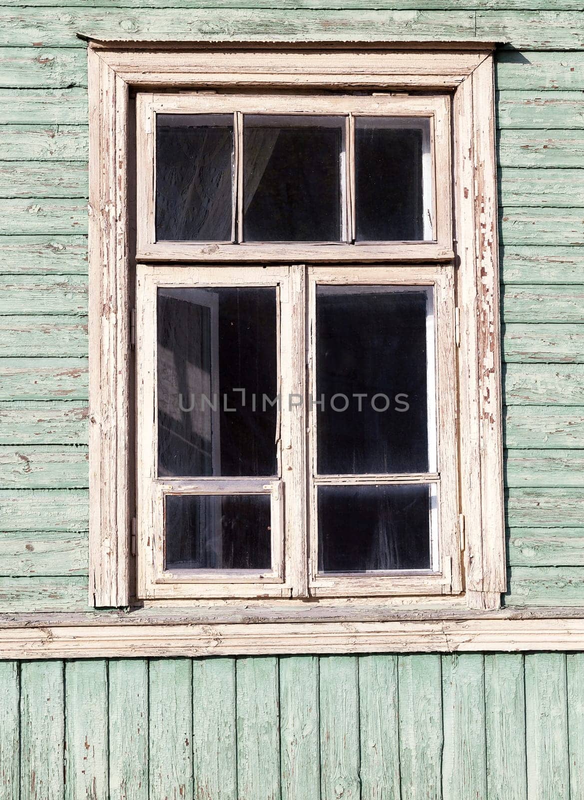 photographed close-up of the old wooden houses with windows. In the green house no one lives