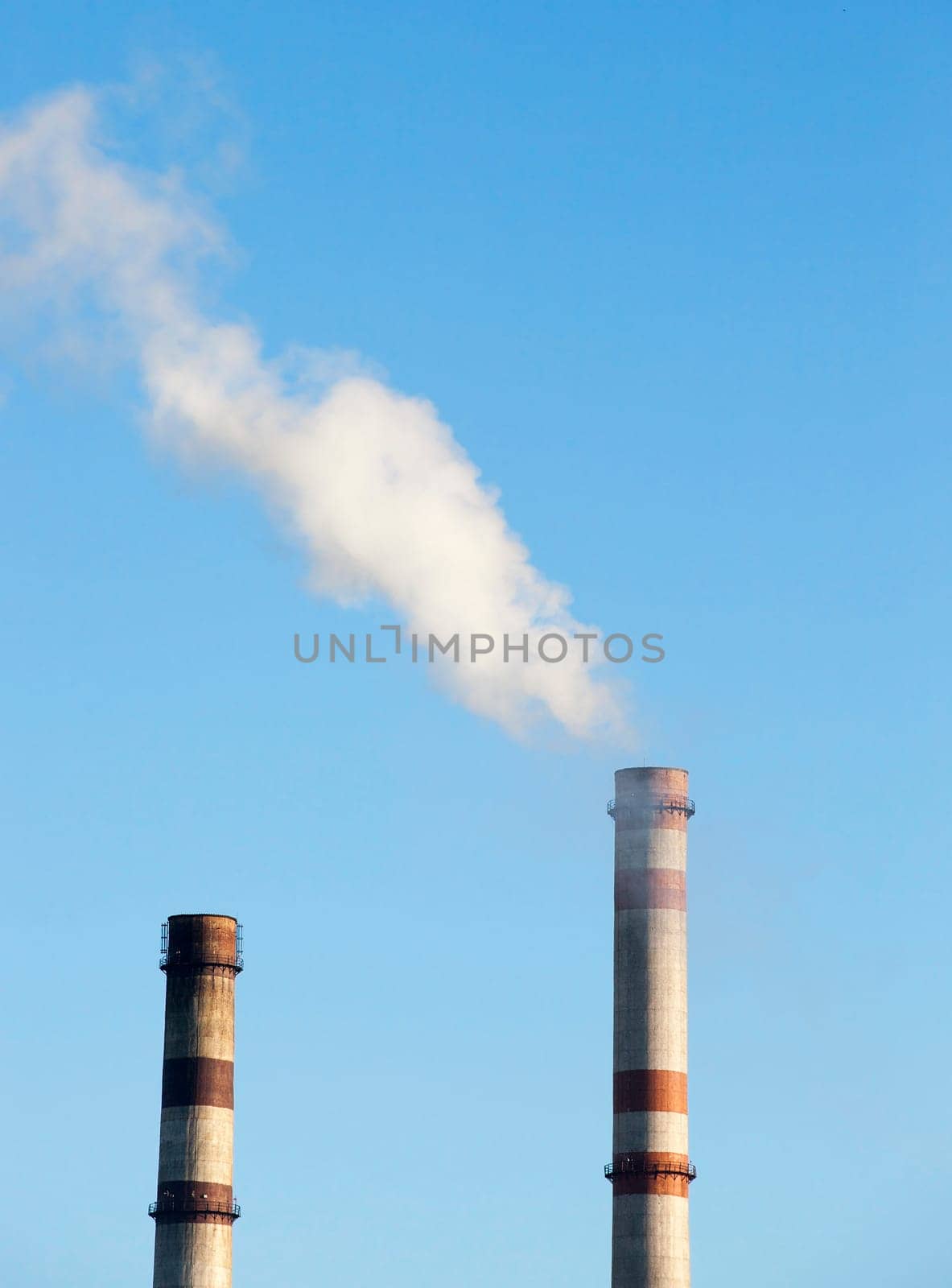 power plant with smoke pipe during operation. Photo from a distance close-up. Blue sky in autumn season