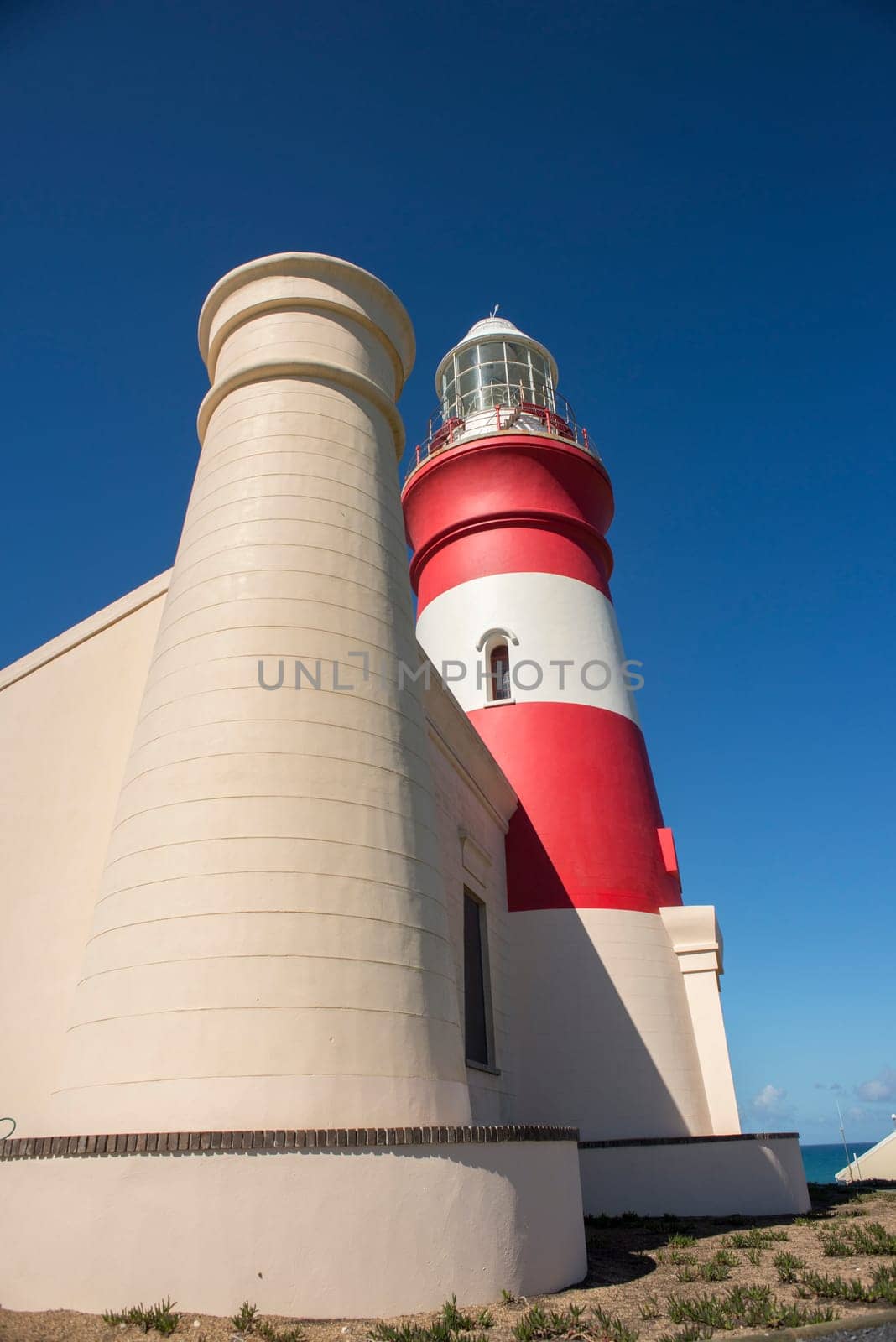 A view of Cape Agulhas Lighthouse from the side with one of the towers in the foreground.