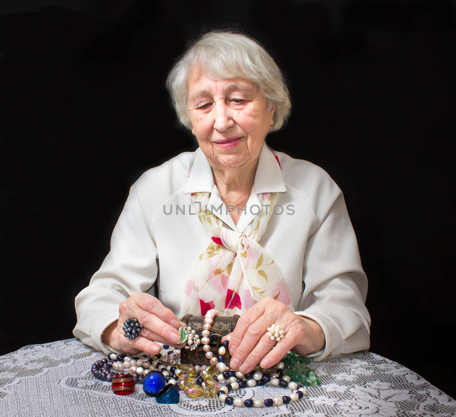 Senior woman sitting and going through in the hands of jewelry pearl
