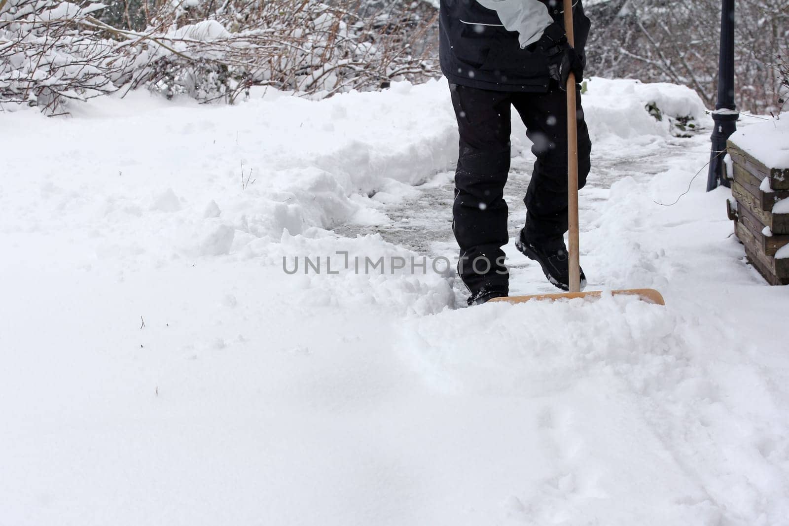 A man clears snow from a footpath in winter
