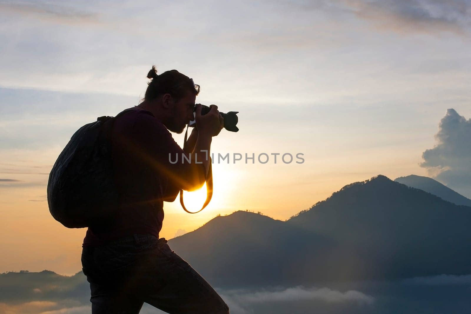 Photographer Hiker walking along,  takes pictures and meets sunrise on the mountain - Stock image