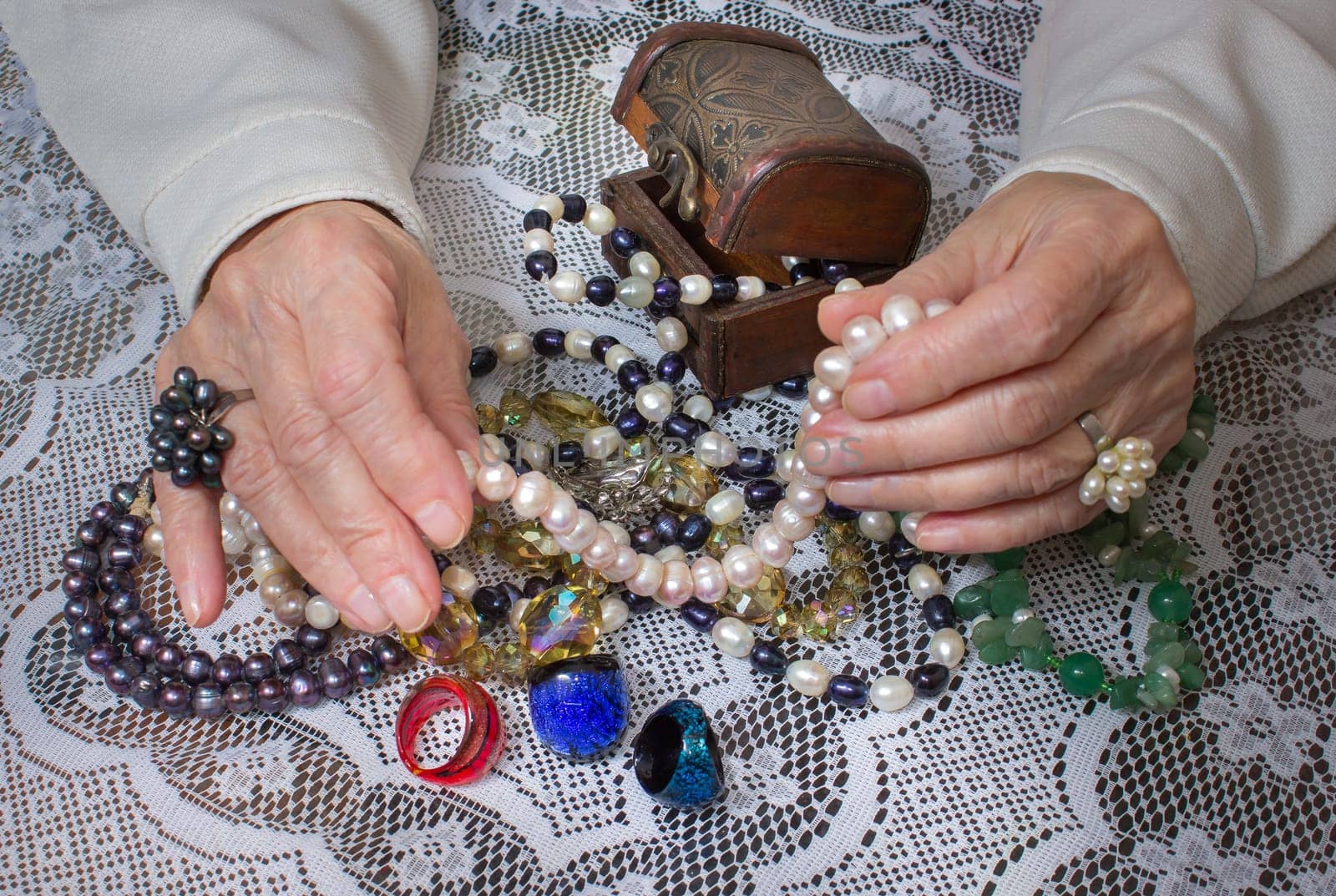 Senior woman sitting and going through in the hands of jewelry pearl
