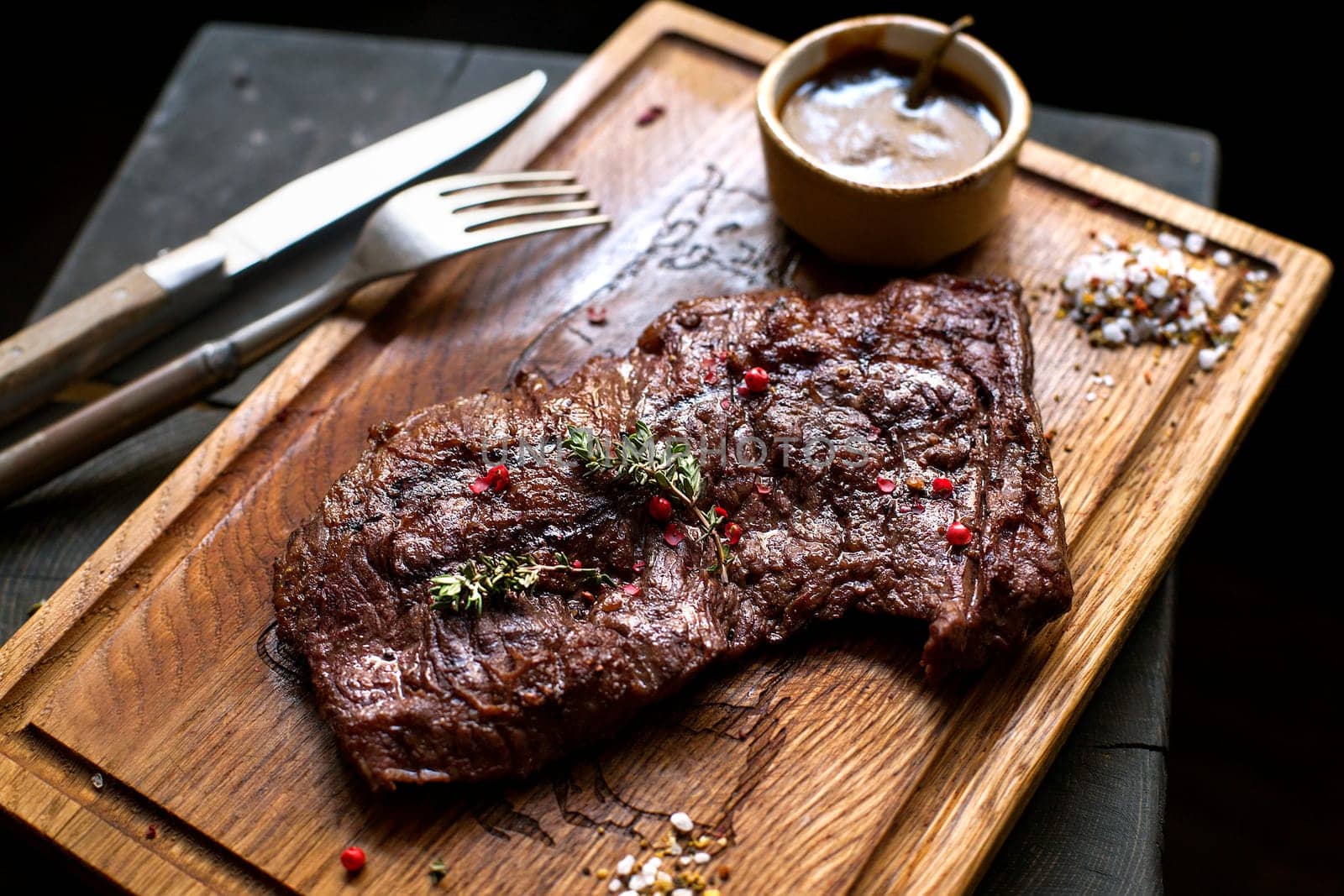 Beef steak. Piece of  Grilled BBQ beef marinated in spices and herbs on a rustic wooden board over rough wooden desk with a copy space. Top view. Stock Image