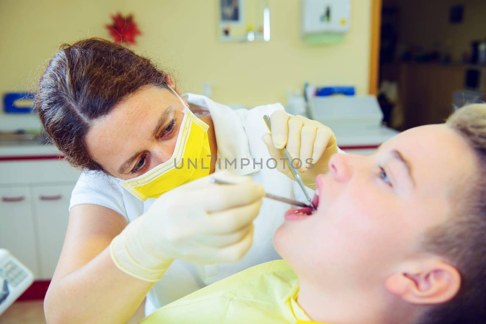 teenager is treated by female dentist in dental surgery