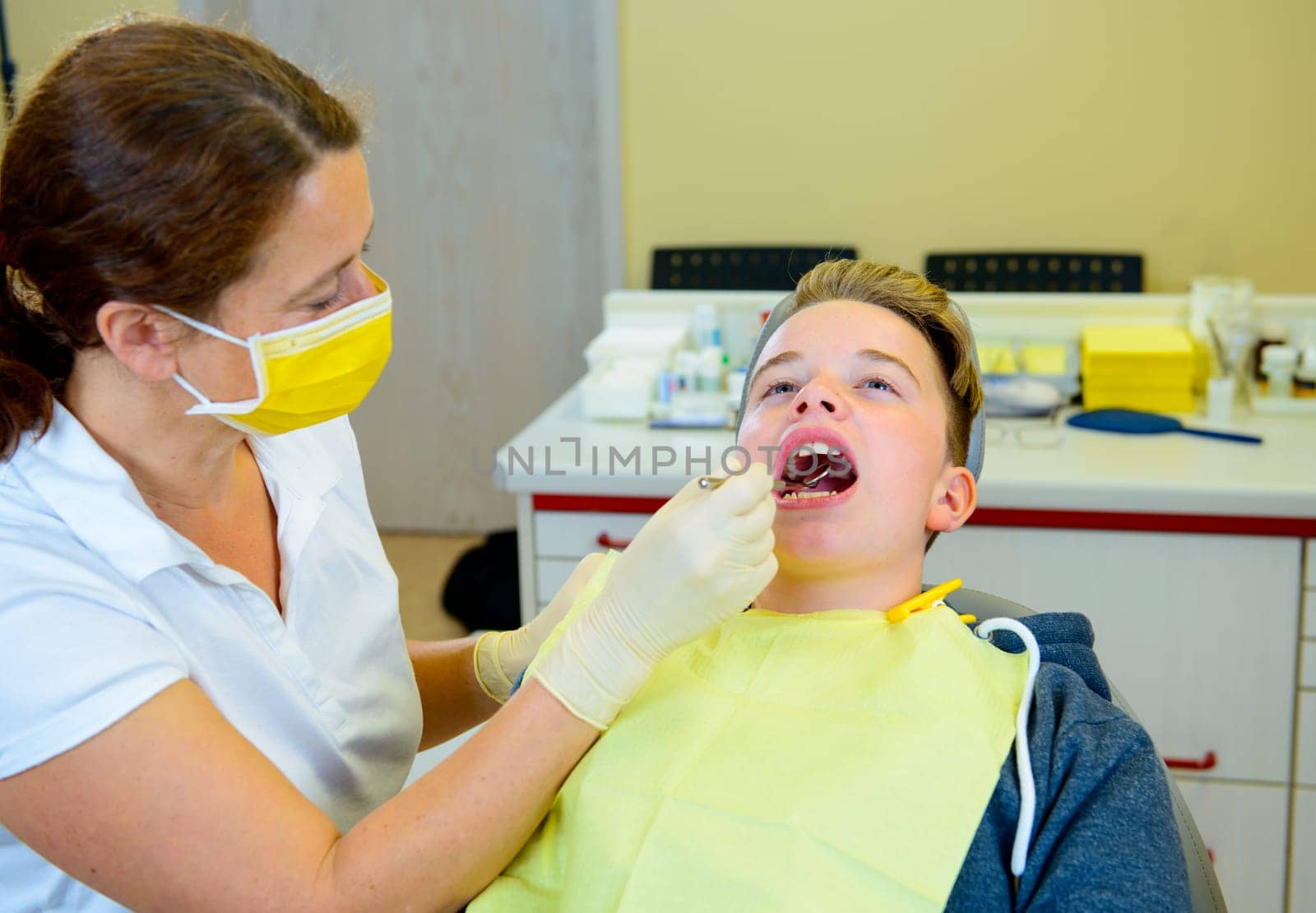 teenager is treated by female dentist in dental surgery