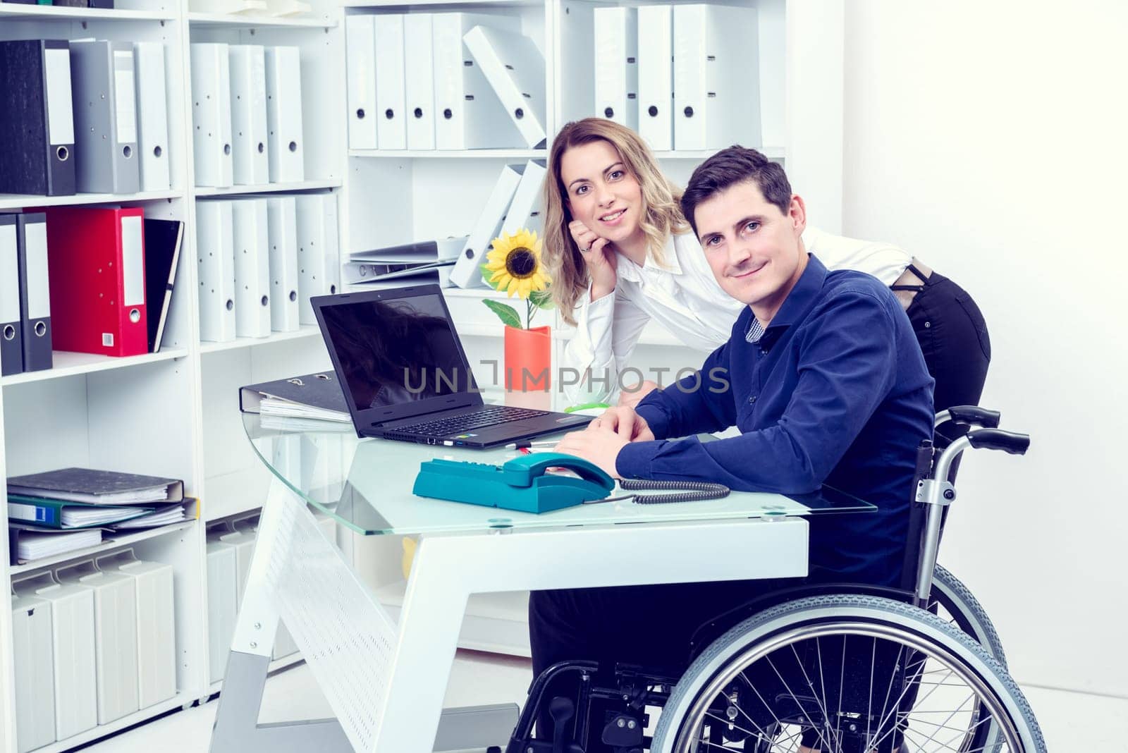 disabled businessman in wheelchair and his female colleague